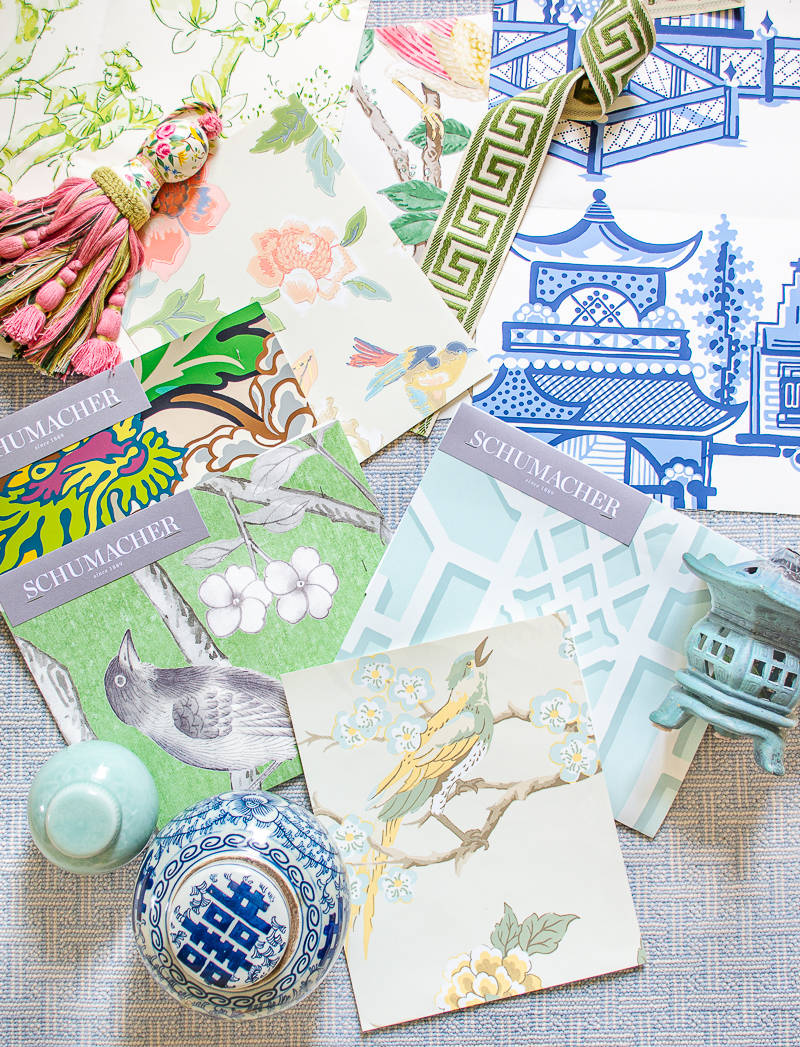 Chinoiserie 桌布 壁紙 — Schumacher 壁紙樣本的平鋪展示，帶有花卉鳥類圖案和藍色寶塔圖案，並以流蘇和陶瓷裝飾點綴。