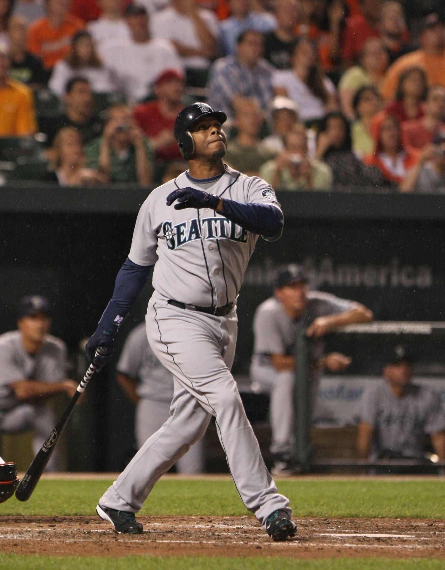 棒球選手在夜間比賽中揮棒，背景有觀眾。 — MLB 壁紙