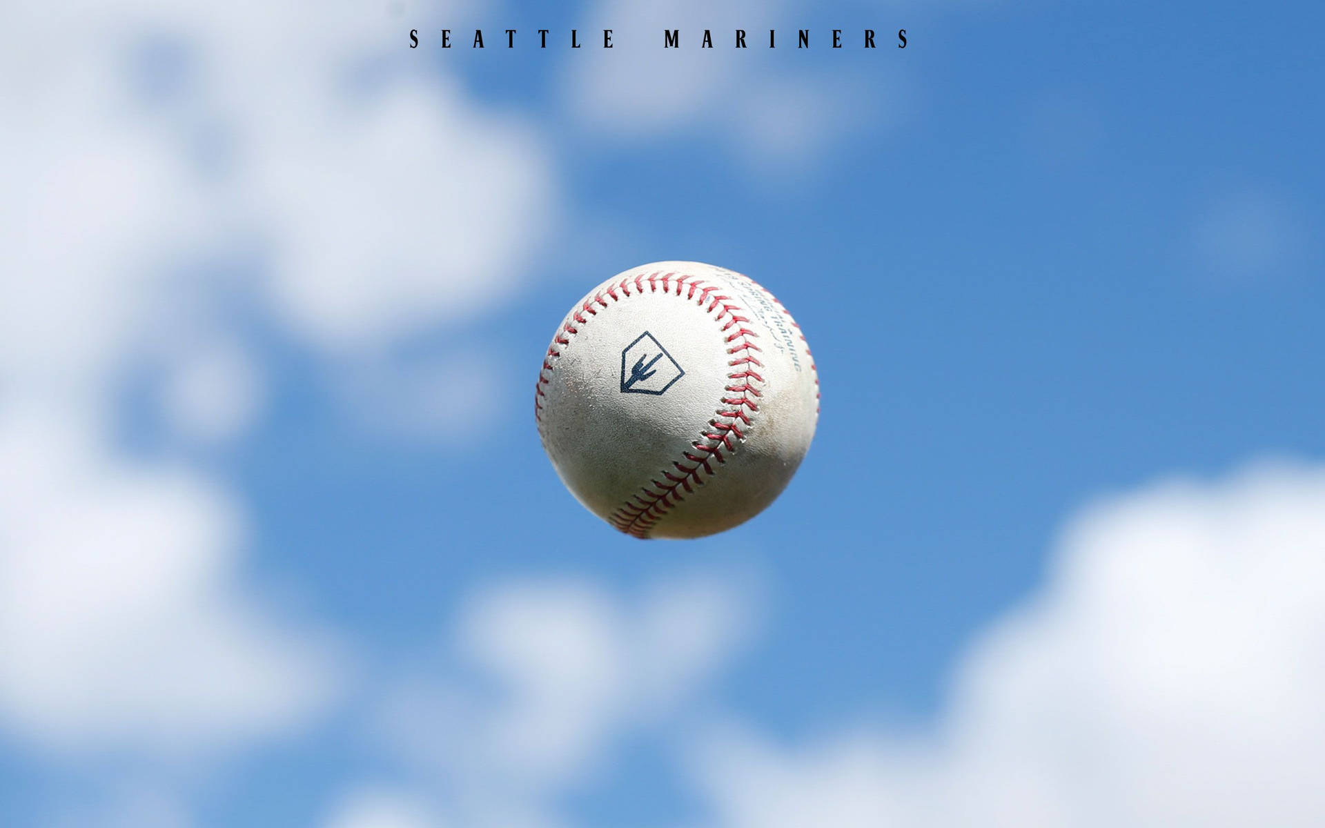一顆帶有西雅圖水手隊標誌的棒球在藍天白雲中飛翔。 — MLB 壁紙
