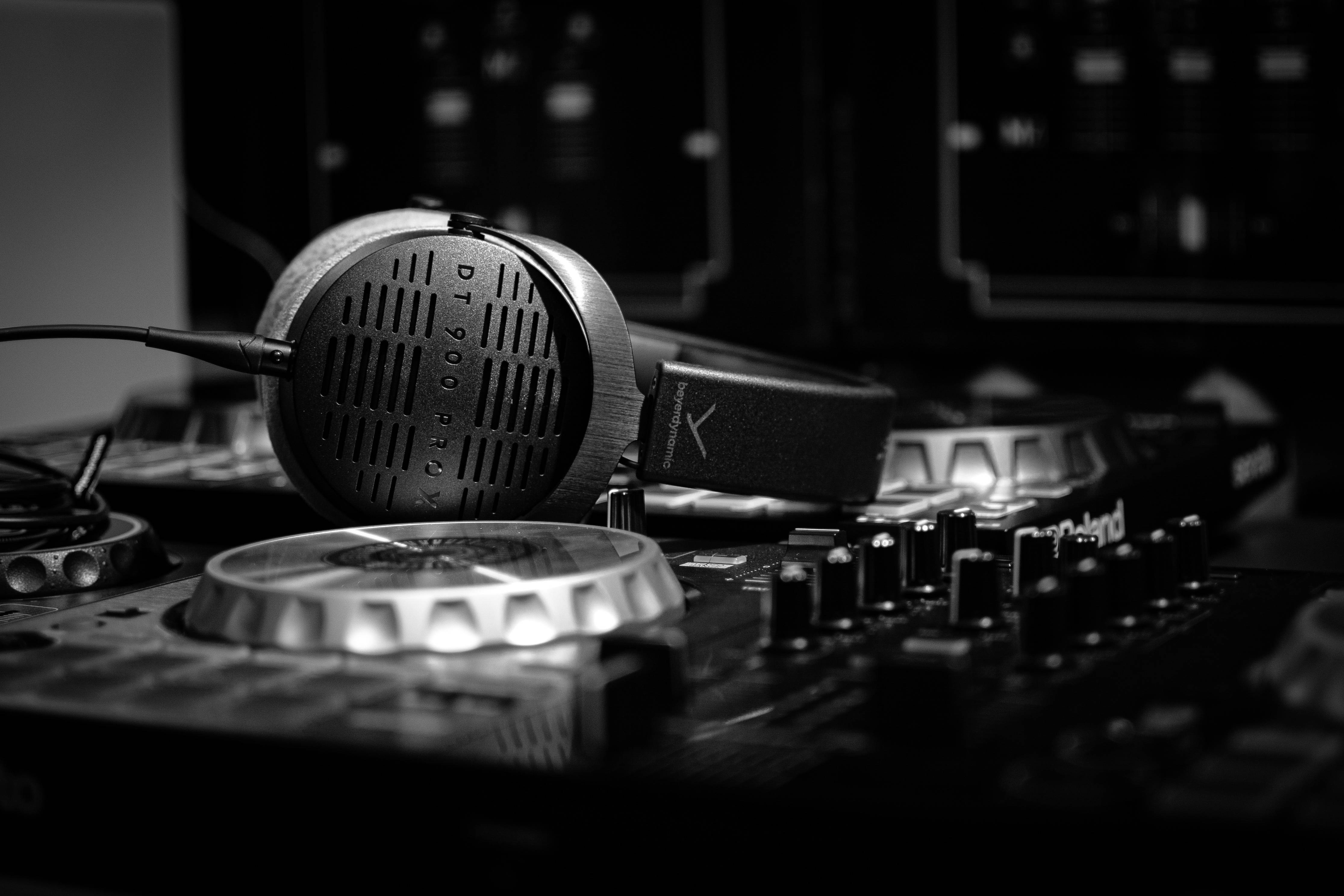 美學 桌布 壁紙 — Sennheiser耳機放在DJ混音器上的單色特寫，背景有發光的旋鈕和模糊的螢幕。