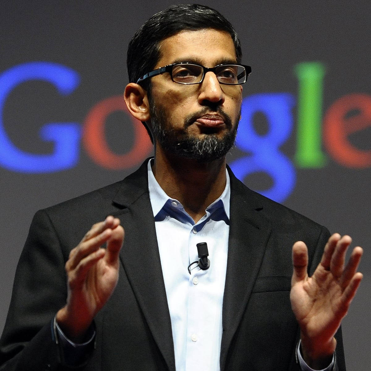 google 桌布 壁紙 — Sergey Brin 在Google活動中戴著眼鏡和黑色西裝，在色彩繽紛的標誌背景前發言。