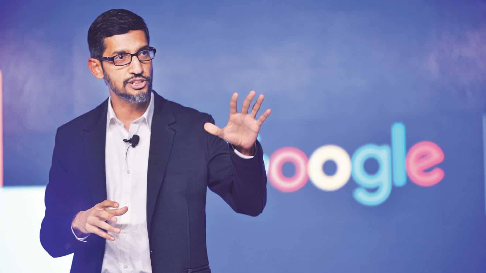 google 桌布 壁紙 — Sergey Brin 在Google活動中發言時做手勢，背景為藍色和彩色Google標誌。