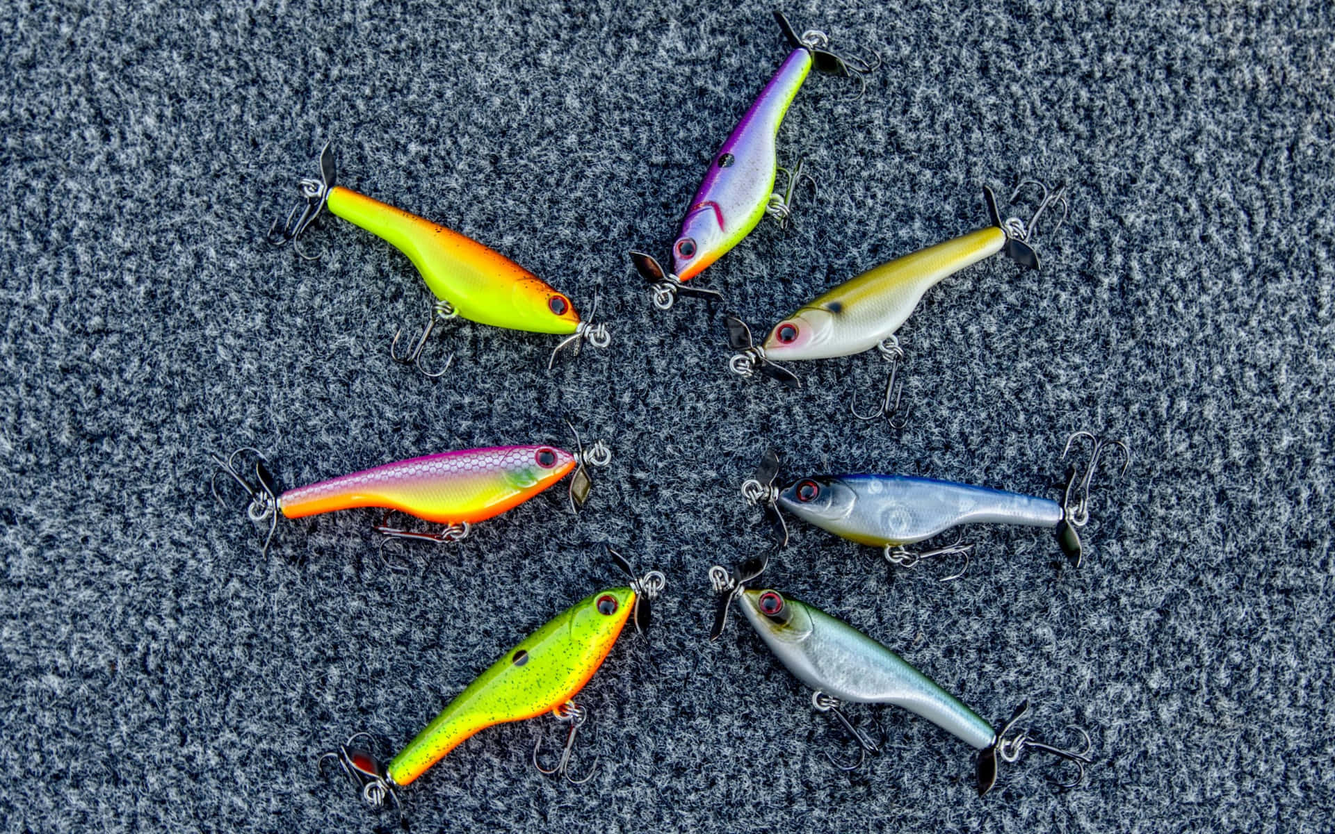  壁紙 — 七個色彩繽紛的魚餌連魚鉤在紋理灰色地毯上排列成星形圖案。