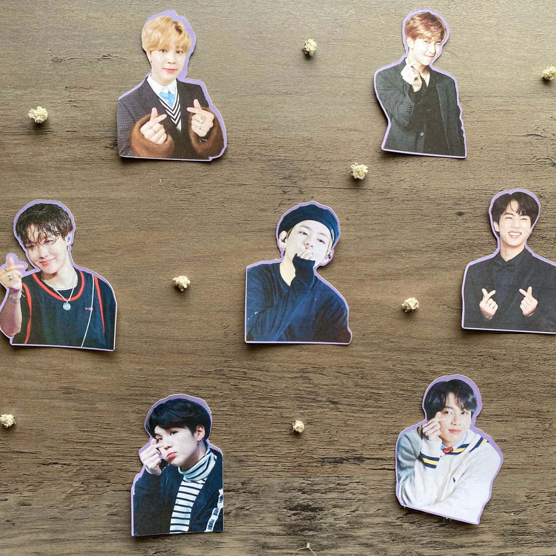 七張K-pop偶像剪裁用小裝飾釘固定在木質表面上。 — Bts 壁紙