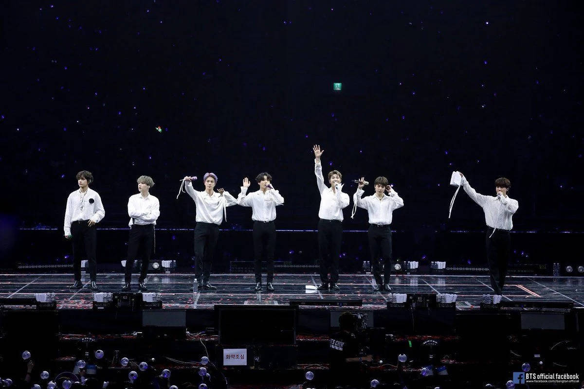 七位K-pop偶像在燈光璀璨的舞台上表演，背景是星空，粉絲們在歡呼。 — Bts 壁紙