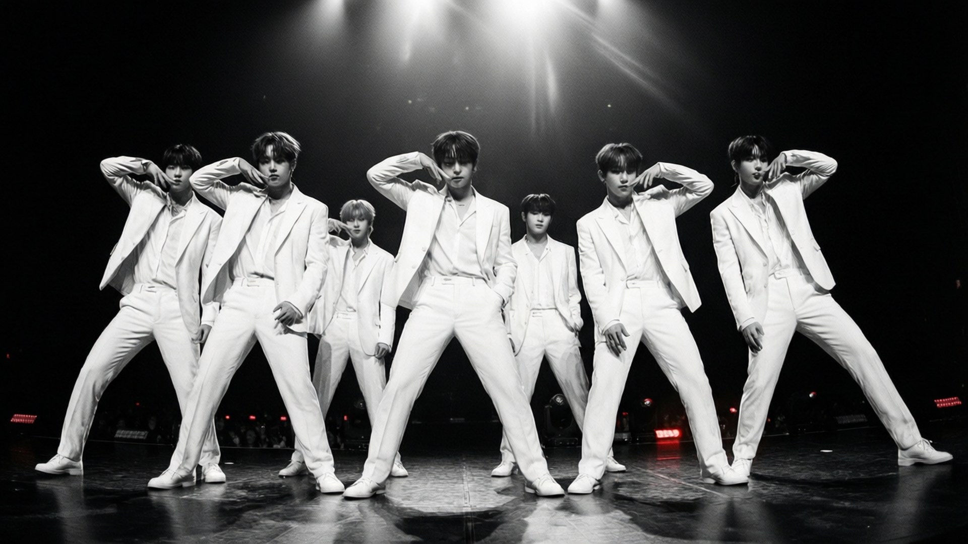 七位身穿白色西裝的男士在深色舞台上於明亮燈光下擺姿勢。 — K Pop 壁紙