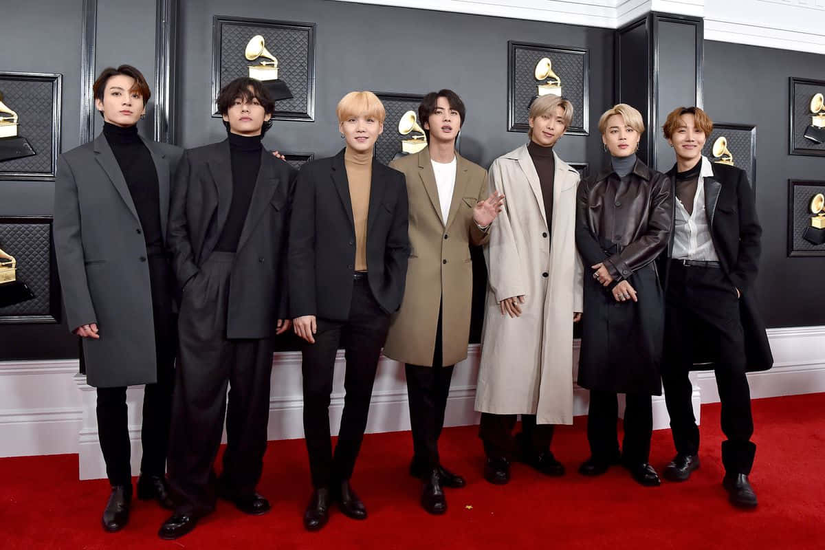 七位穿著時尚大衣的男士在葛萊美獎活動的紅地毯上擺姿勢。 — Bts 壁紙