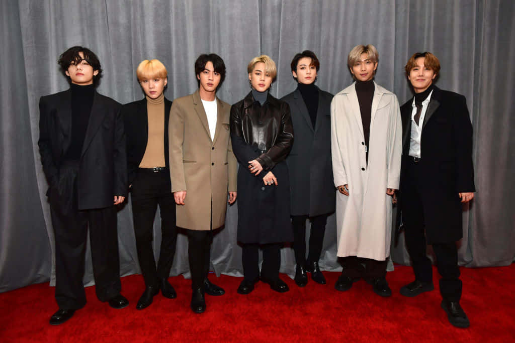 七位男士身著時尚服裝在活動中於紅地毯上擺姿勢。 — Bts 壁紙