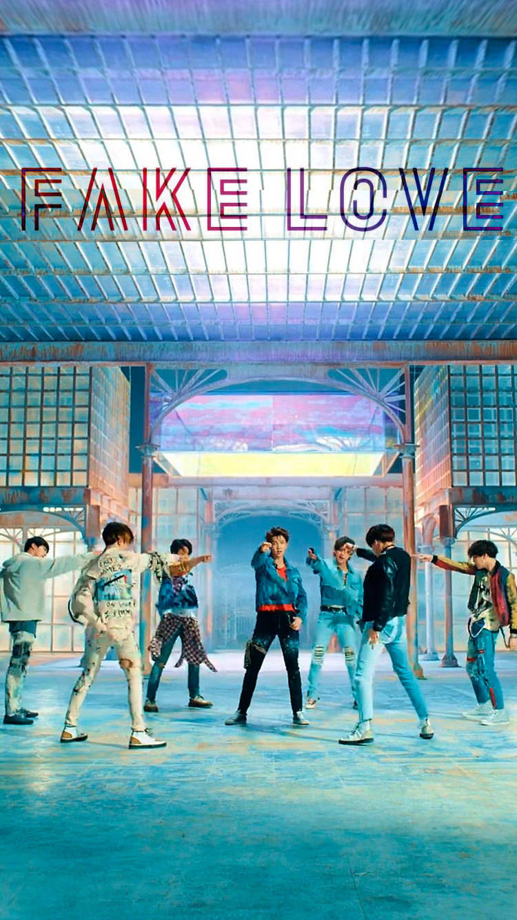 七位K-pop偶像在未來感藍色攝影棚中戲劇性地擺姿勢，上方有「FAKE LOVE」文字。 — K Pop 壁紙