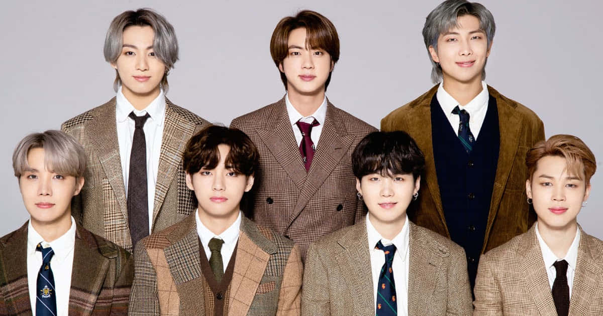 七位K-pop偶像穿著相配的棕色格子西裝，為工作室肖像擺姿勢。 — Bts 壁紙