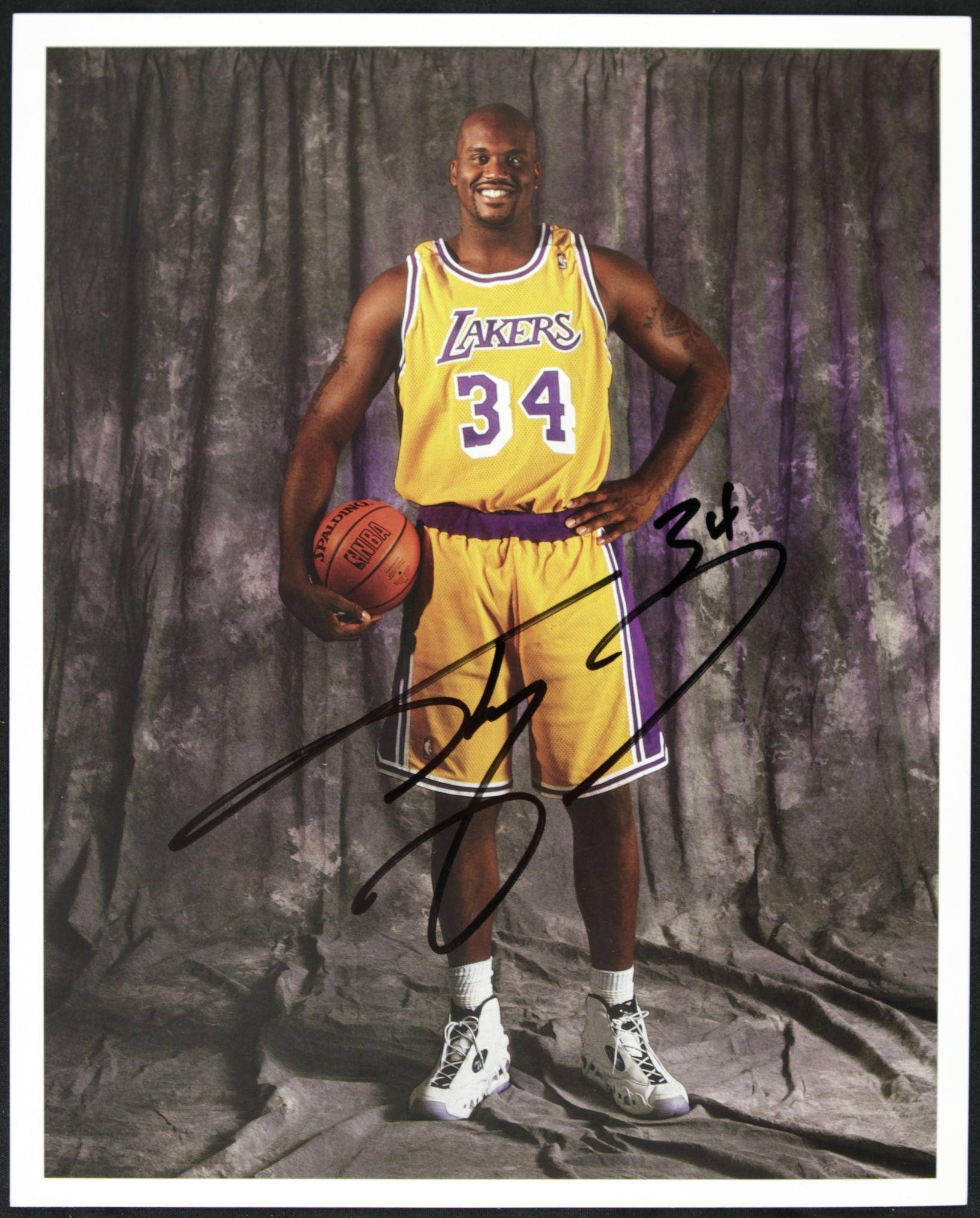 Shaquille O'neal 桌布 壁紙 — Shaquille O'Neal 身穿湖人隊34號球衣，微笑著手持籃球，背景是帶紋理的灰色窗簾。