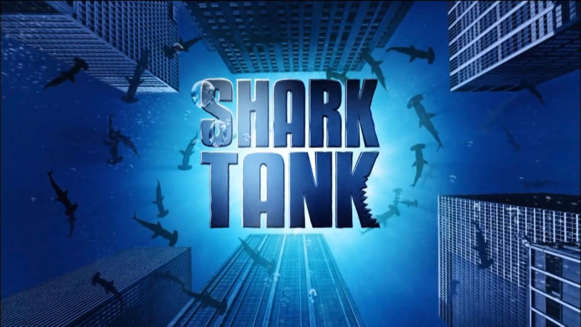  壁紙 — Shark Tank 標誌在水下發出藍光，鯊魚在超現實城市景觀中的摩天大樓之間游來游去。