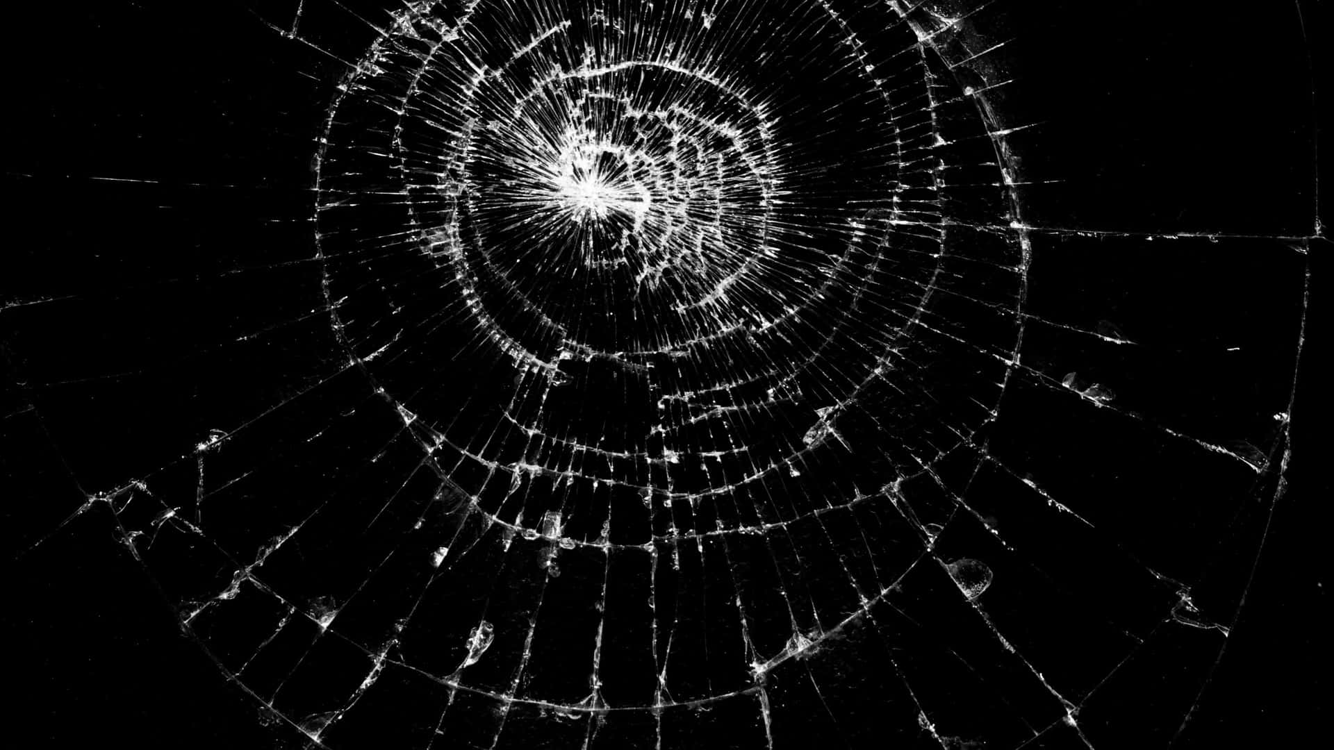  壁紙 — 黑色背景上，從中心撞擊點放射出複雜徑向裂紋的破碎玻璃表面。