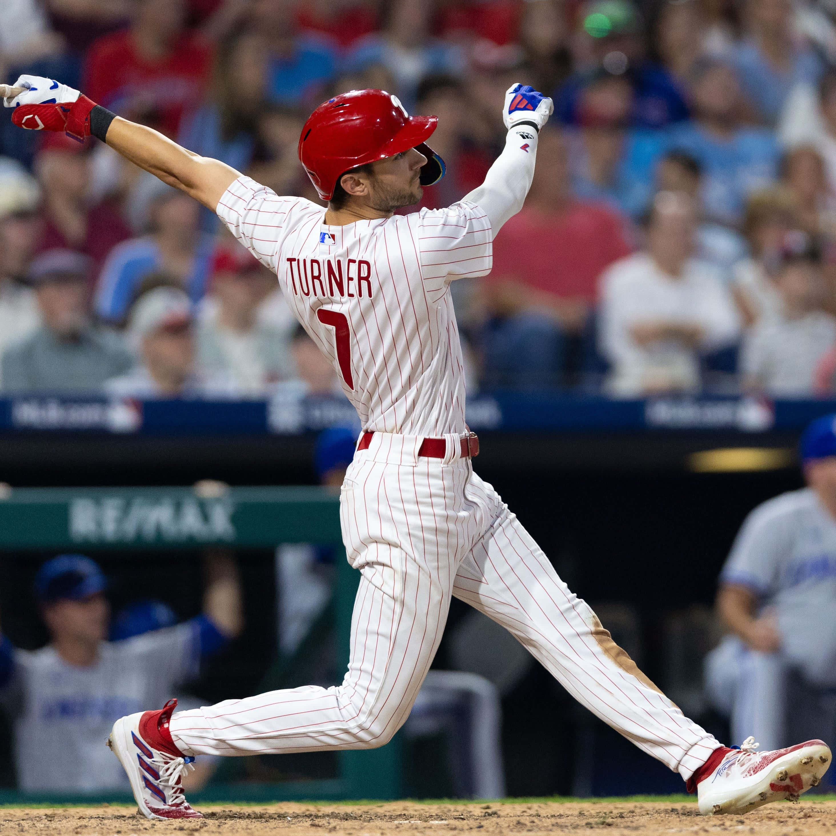 Trea Turner Phillies 桌布 壁紙 — 身穿白色細條紋球衣的棒球選手Turner在夜間比賽中，在球場燈光下高舉雙臂慶祝。