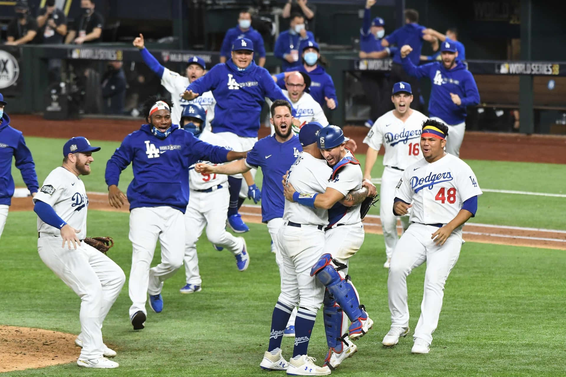  壁紙 — 身穿道奇隊球衣的棒球選手在球場燈光下的綠色場地上瘋狂慶祝。