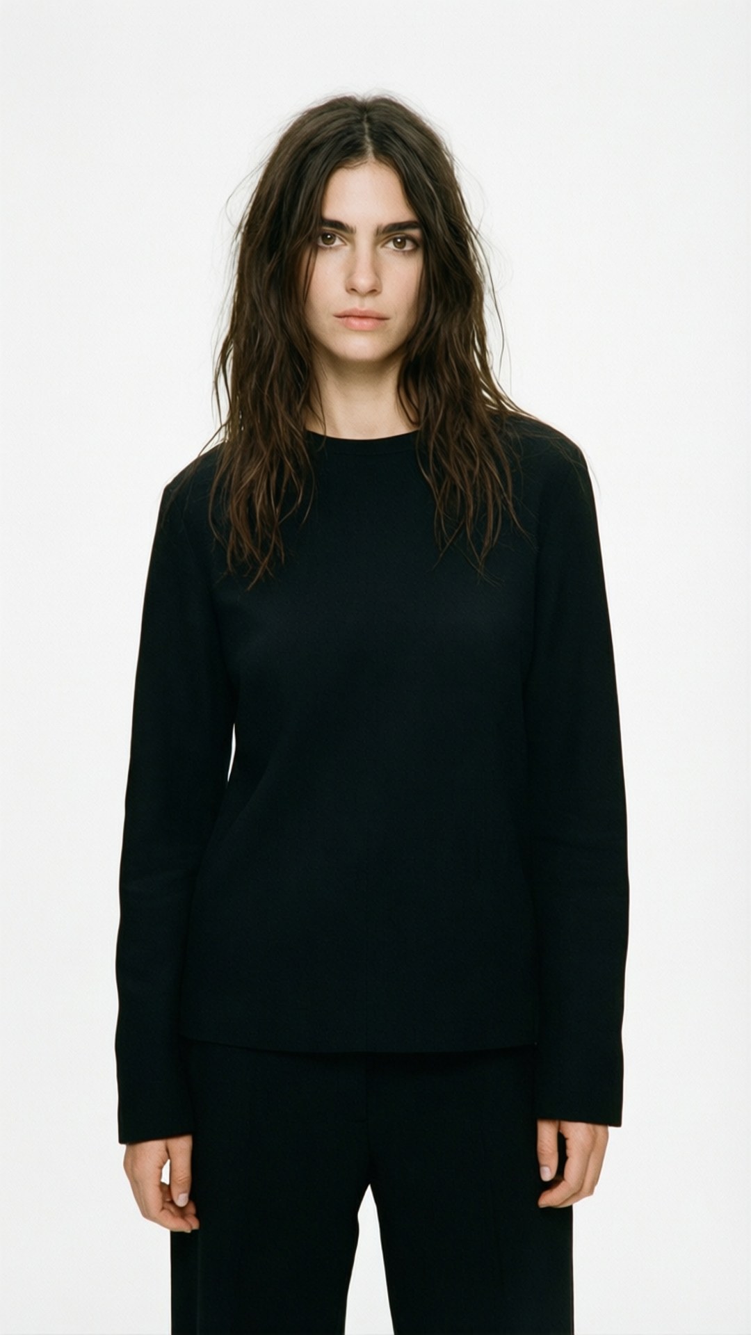 Minimalist Editorial 壁紙 — 一位頭髮凌亂的深色頭髮女性，穿著黑色長袖上衣和黑色褲子，背景為純白色。