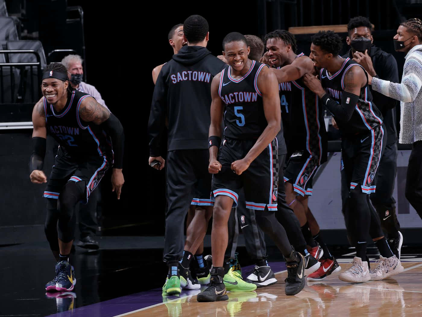 籃球隊穿著黑色制服在球場上慶祝勝利。 — NBA 壁紙