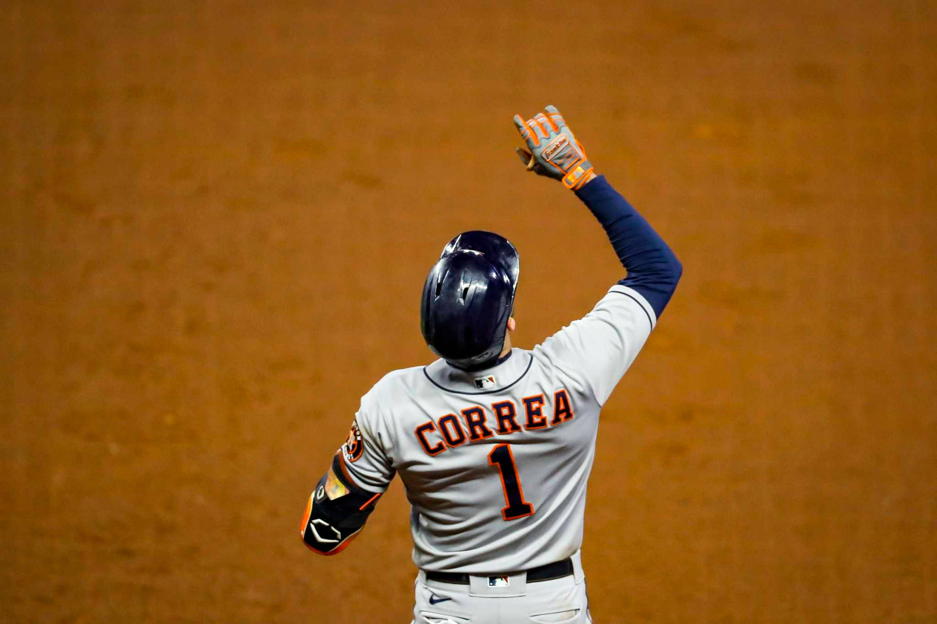 棒球選手Correa在夜晚的泥地場上高舉雙手慶祝。 — MLB 壁紙