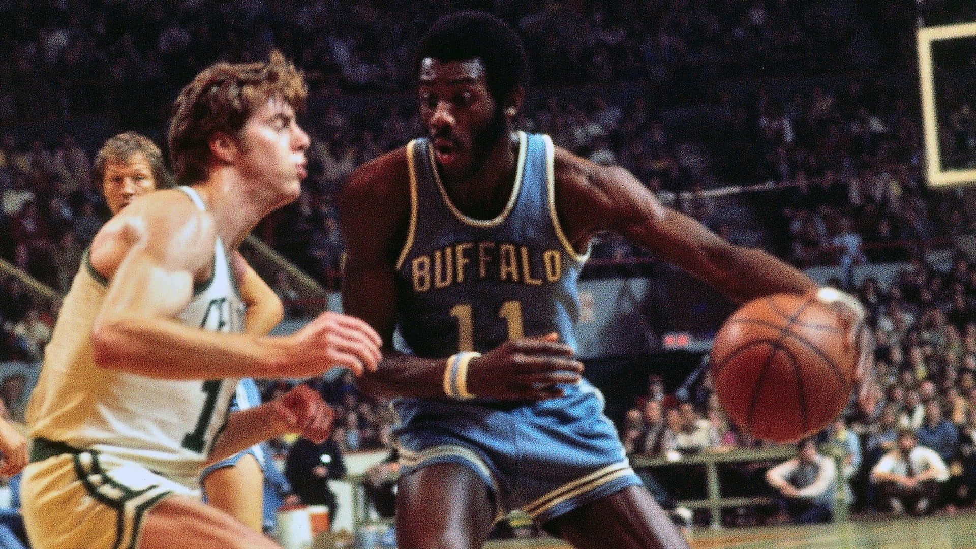 身穿藍色Buffalo球衣的籃球運動員在比賽中運球，背景有觀眾。 — NBA 壁紙