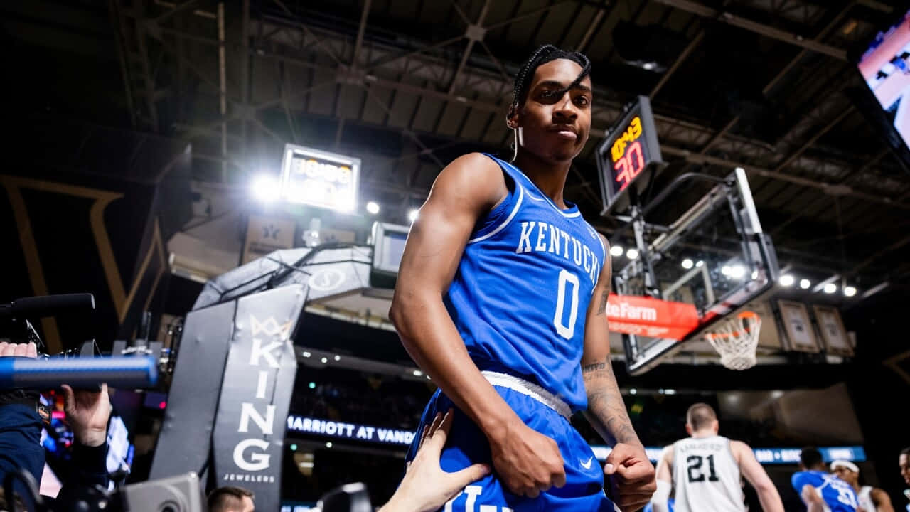 身穿藍色肯塔基球衣的籃球運動員站在球場上，身後有籃框。 — NBA 壁紙