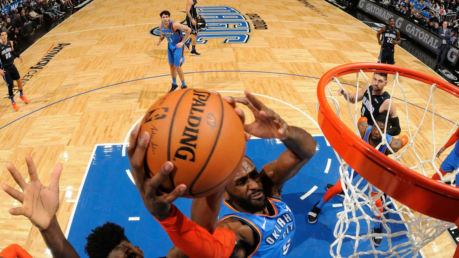 身穿藍色球衣的籃球運動員灌籃，防守球員試圖封阻。 — NBA 壁紙
