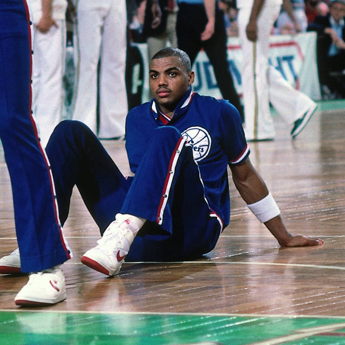 身穿藍色球衣的籃球運動員坐在木地板上 — NBA 壁紙
