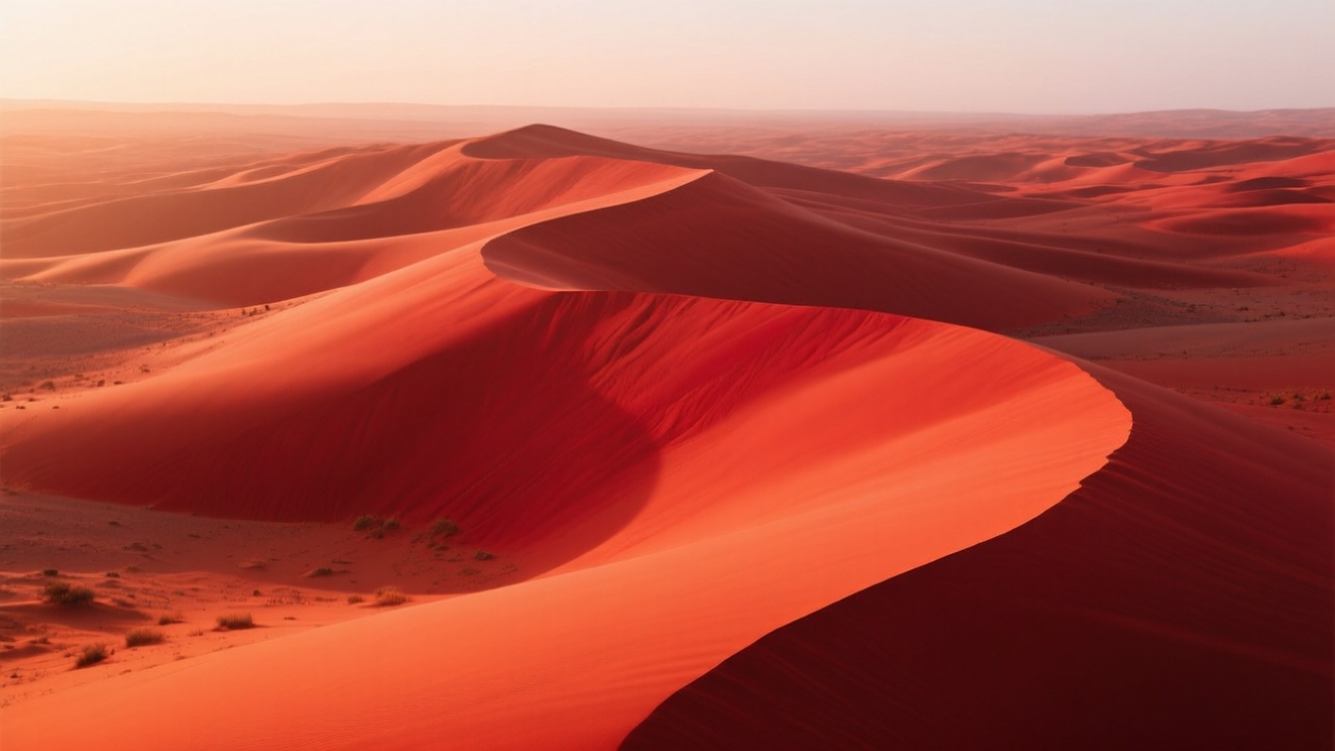 Nefud Red Dunes 壁紙 — 深紅色沙丘在柔和的金色日落天空下優雅地蜿蜒起伏。