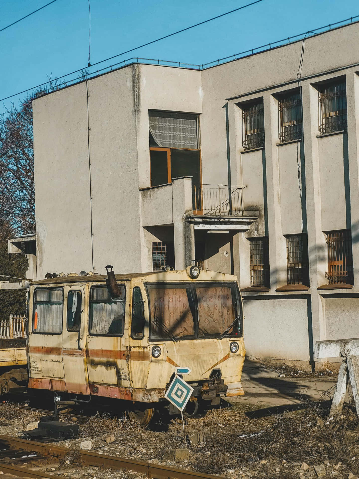  壁紙 — 一輛生鏽廢棄的電車被遺忘在風化建築旁，天空湛藍清澈。