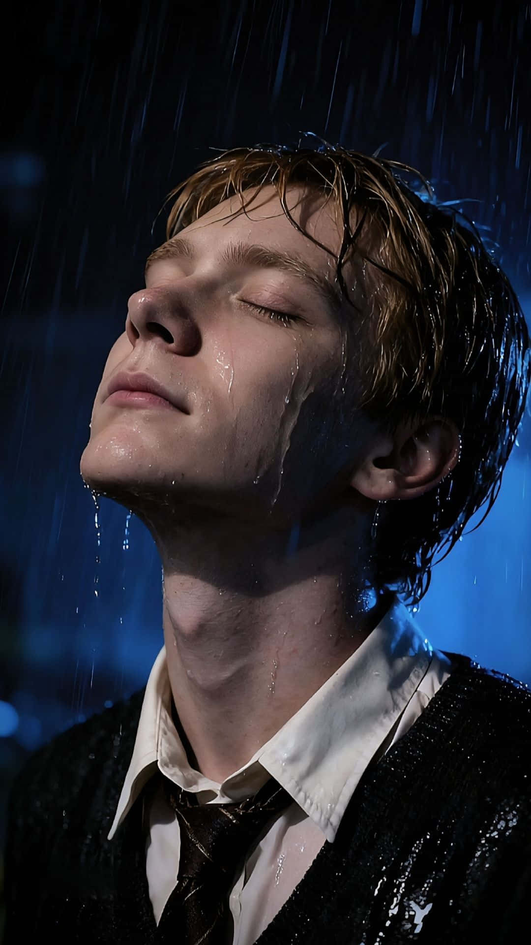  壁紙 — 一個濕髮的年輕男子在深藍色背景下閉上眼睛，雨水順著他的臉流下。