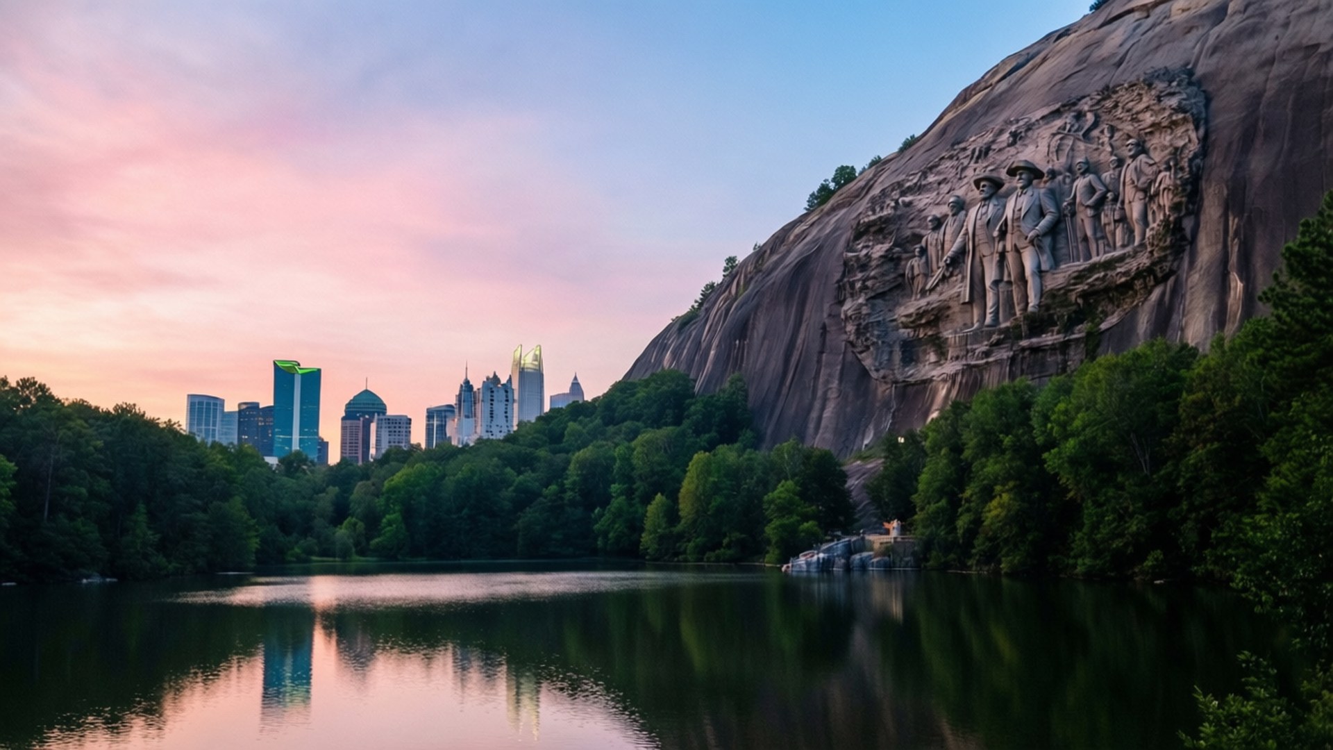 Stone Mountain Sunrise 壁紙 — 石山公園寧靜的日落，花崗岩面上雕刻的南方邦聯紀念碑在平靜的湖面上方清晰可見，湖面倒映著城市天際線。
