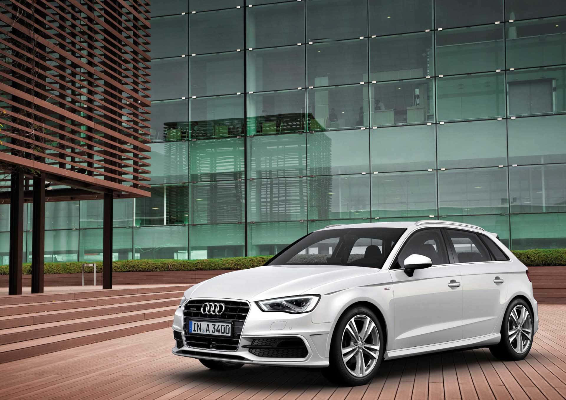 Audi A3 桌布 壁紙 — 一輛時尚的白色奧迪旅行車停在現代玻璃和木造建築前的木質平台上。