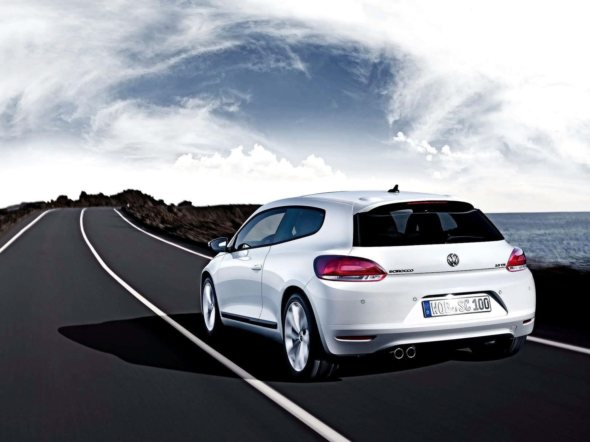 Volkswagen Scirocco 桌布 壁紙 — 一輛時尚的白色福斯Scirocco在戲劇性的多雲天空下行駛於沿海公路。