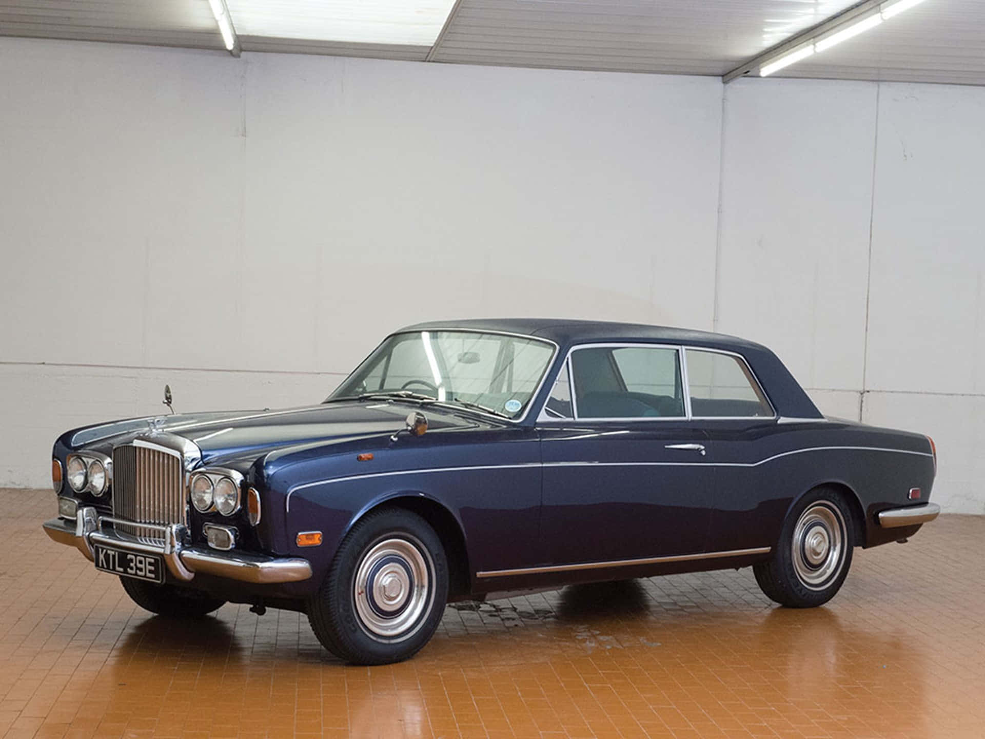 Bentley T1 桌布 壁紙 — 一架時尚的海軍藍經典賓利S3轎跑車在乾淨的瓷磚車庫中，在明亮的燈光下閃閃發光。