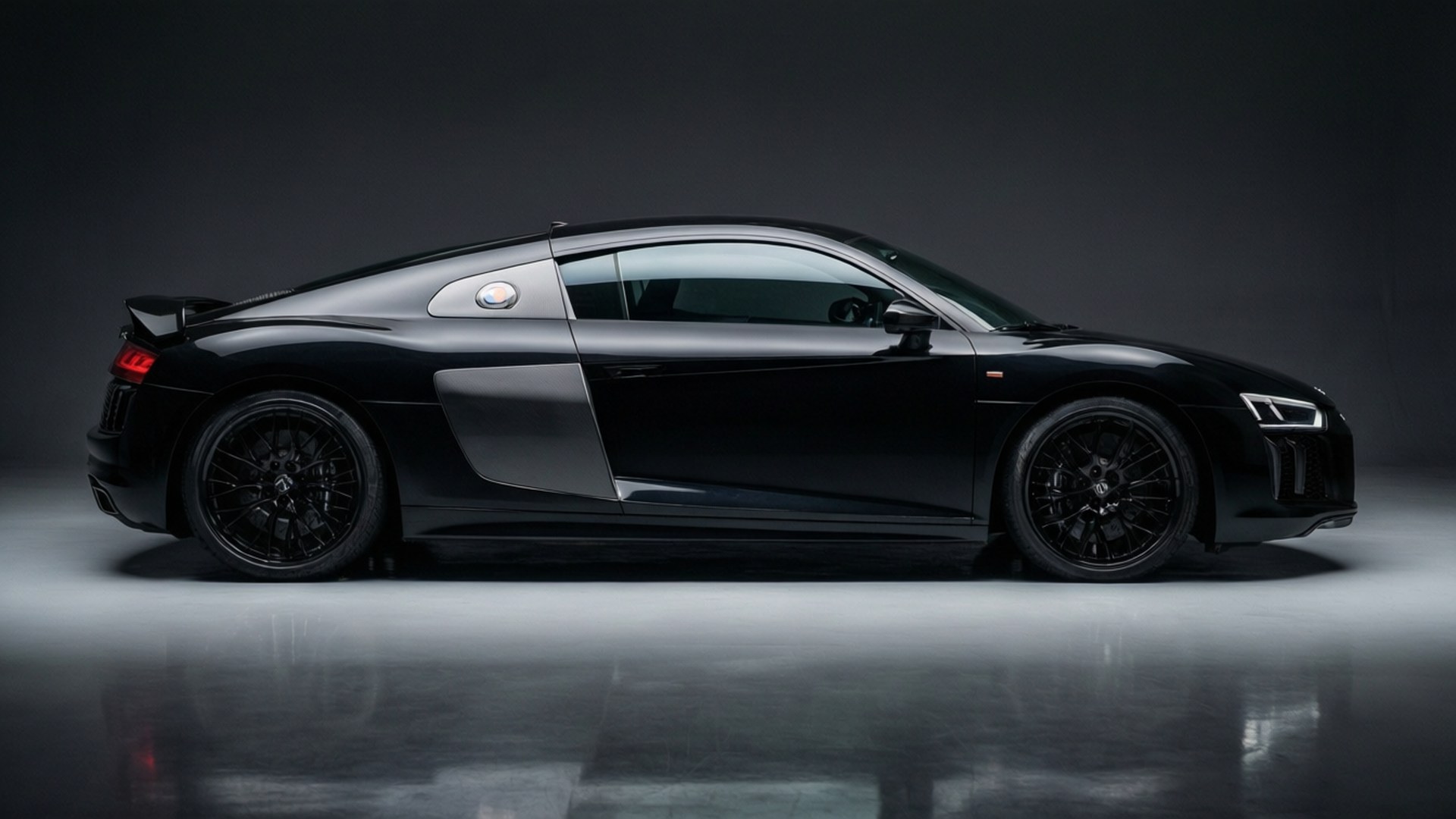 Audi R8 Studio 壁紙 — 一輛時尚的黑色奧迪R8跑車在深色工作室背景和反光地板上以側面展示。