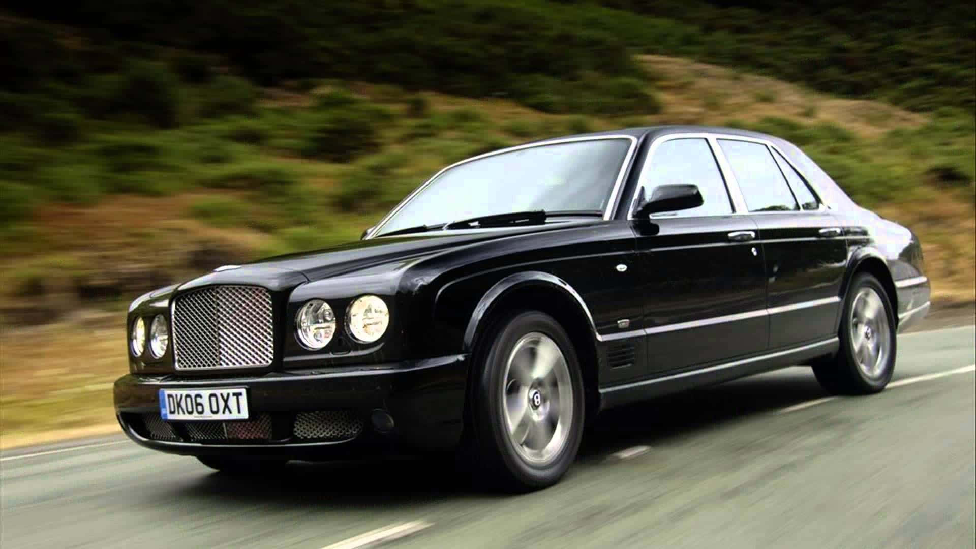 Bentley Arnage 桌布 壁紙 — 一輛時尚的黑色賓利轎車沿著蜿蜒的道路疾馳，模糊的綠色山丘飛速掠過。