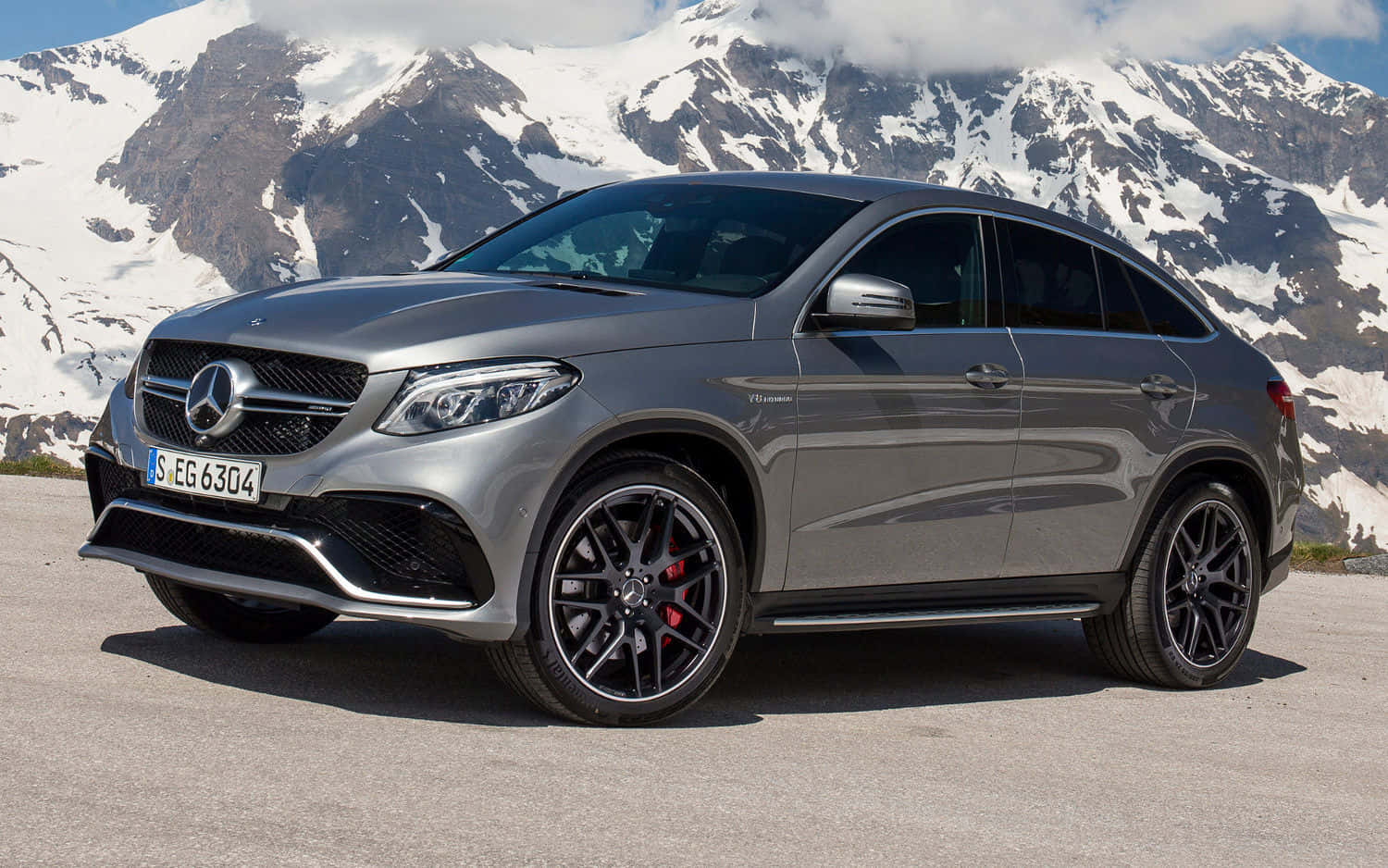 Mercedes Benz Gle-class 桌布 壁紙 — 一架時尚的銀色Mercedes-AMG GLE63 S Coupe停在山路上，背後是白雪覆蓋的山峰，在明亮的日光下。