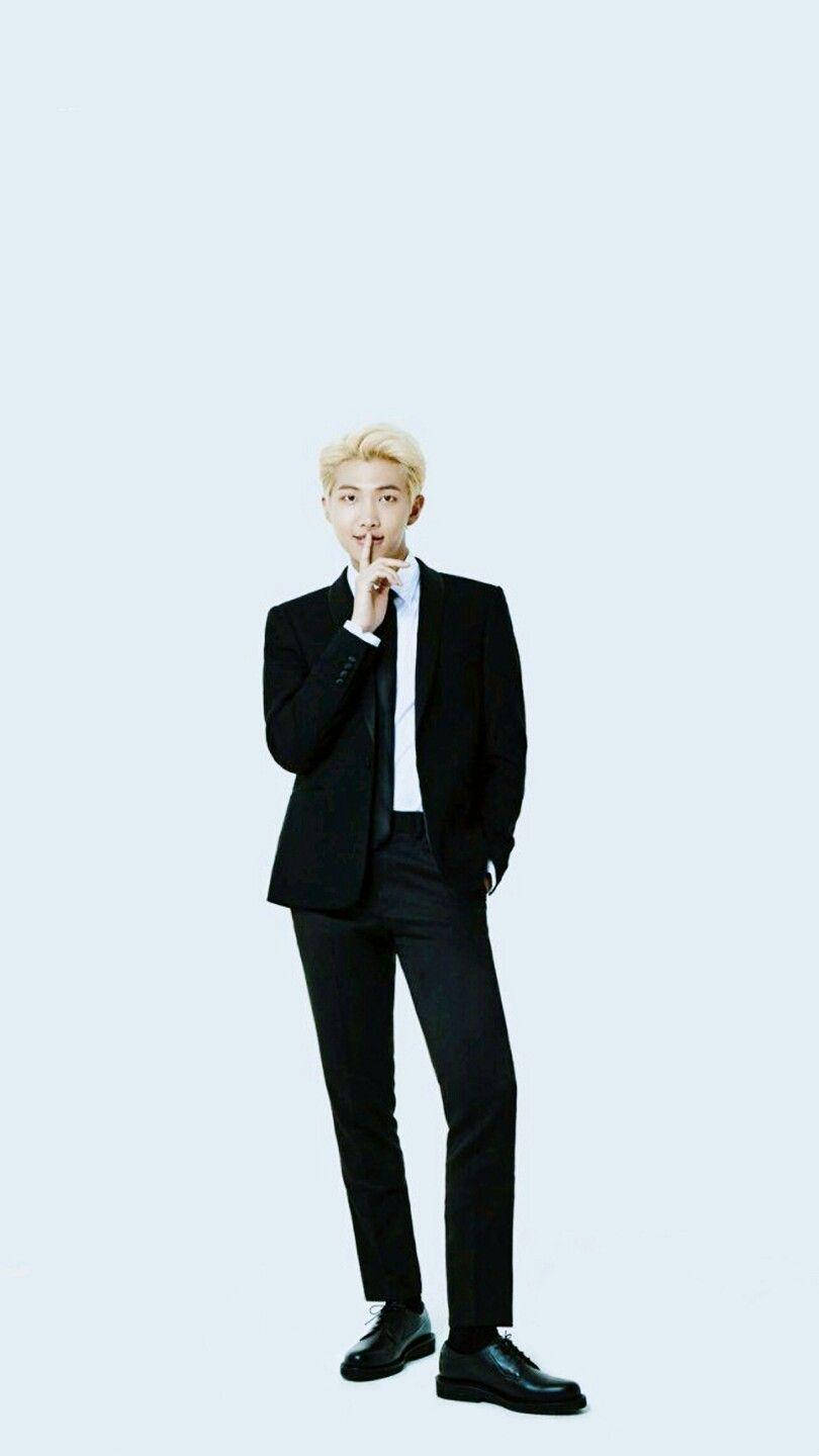 身穿黑色西裝的男士在淺藍色背景前將手指放在唇邊 — Bts 壁紙