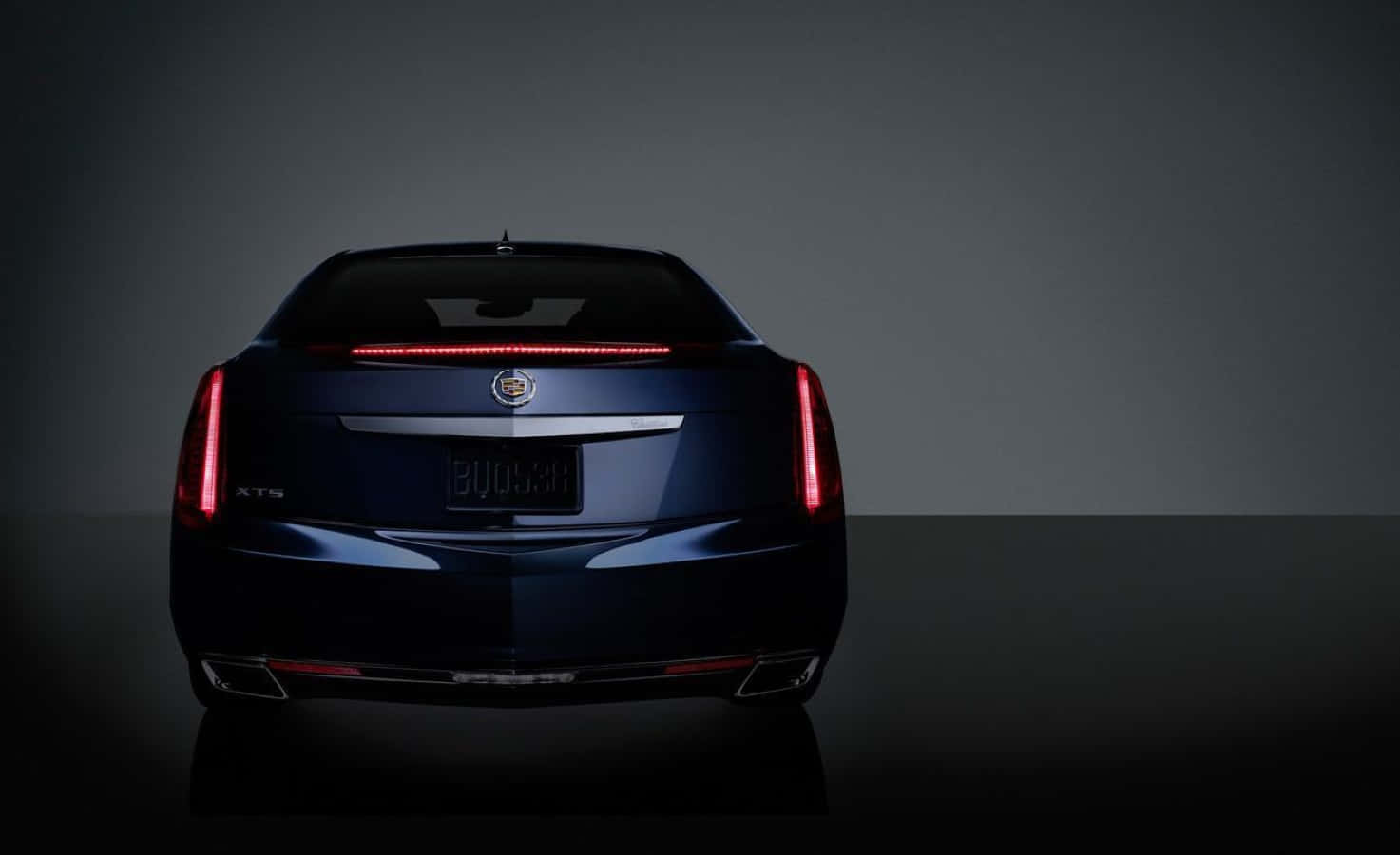 Cadillac Xts 桌布 壁紙 — 時尚深藍色Cadillac XT5的車尾在工作室燈光下，以極簡灰色背景襯托，閃閃發光。