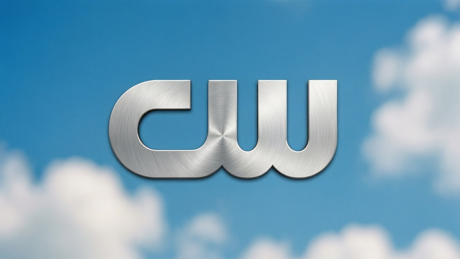 The CW Network 桌布 壁紙 — 閃亮的拉絲金屬CW標誌漂浮在明亮的藍天和柔軟的白雲上。