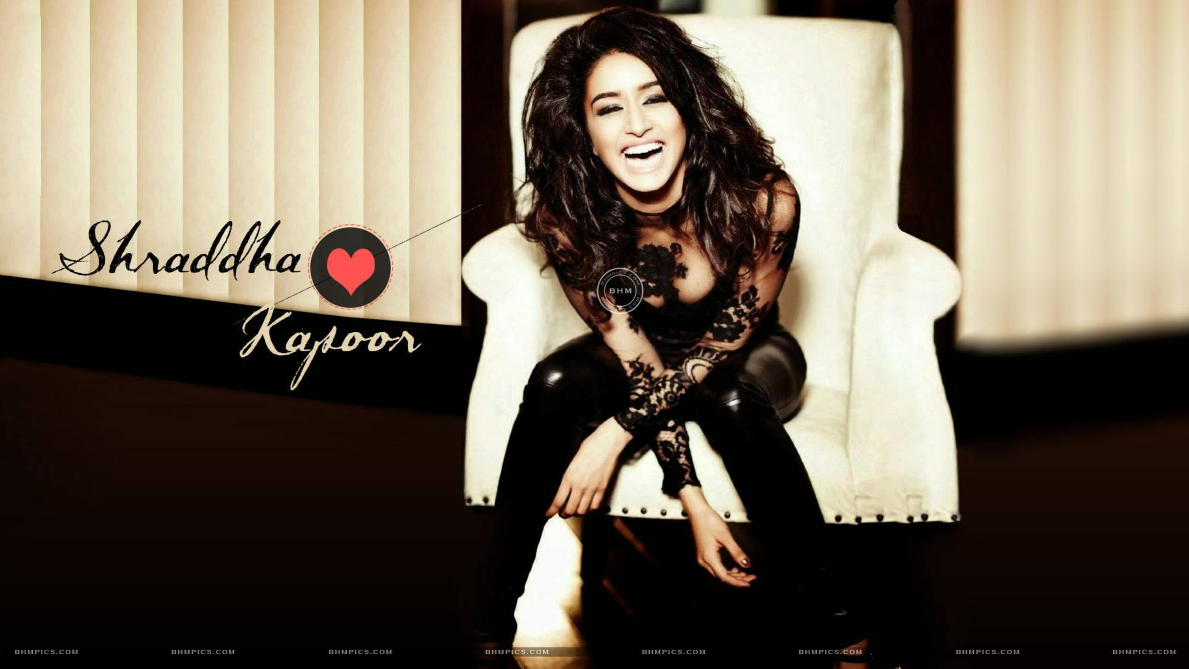 Shraddha Kapoor 桌布 壁紙 — Shraddha Kapoor 坐在白色椅子上，穿著黑色蕾絲服裝，對著條紋牆壁開心地笑。
