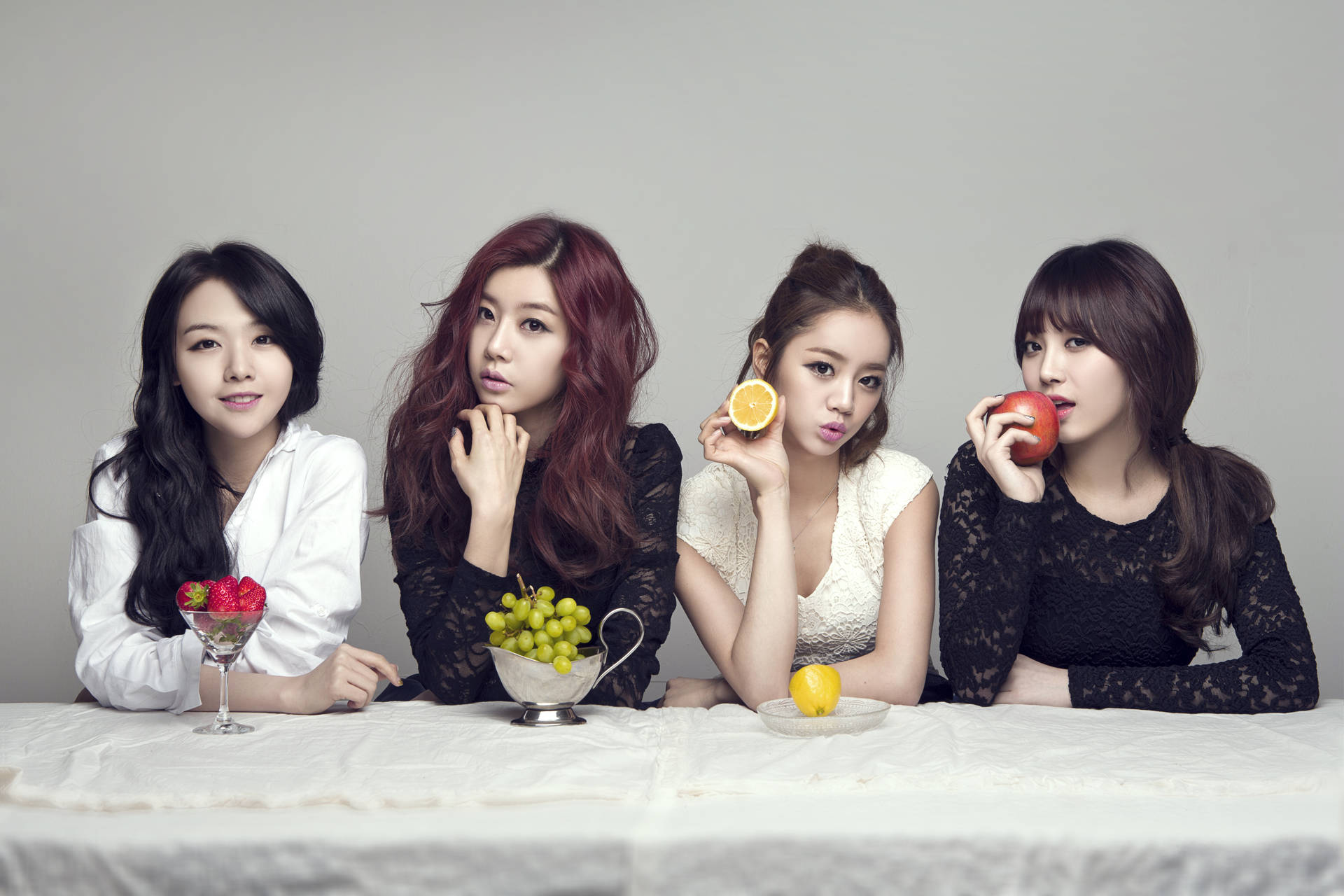 四位女性在攝影棚環境中，與桌上的水果一起擺姿勢。 — K Pop 壁紙
