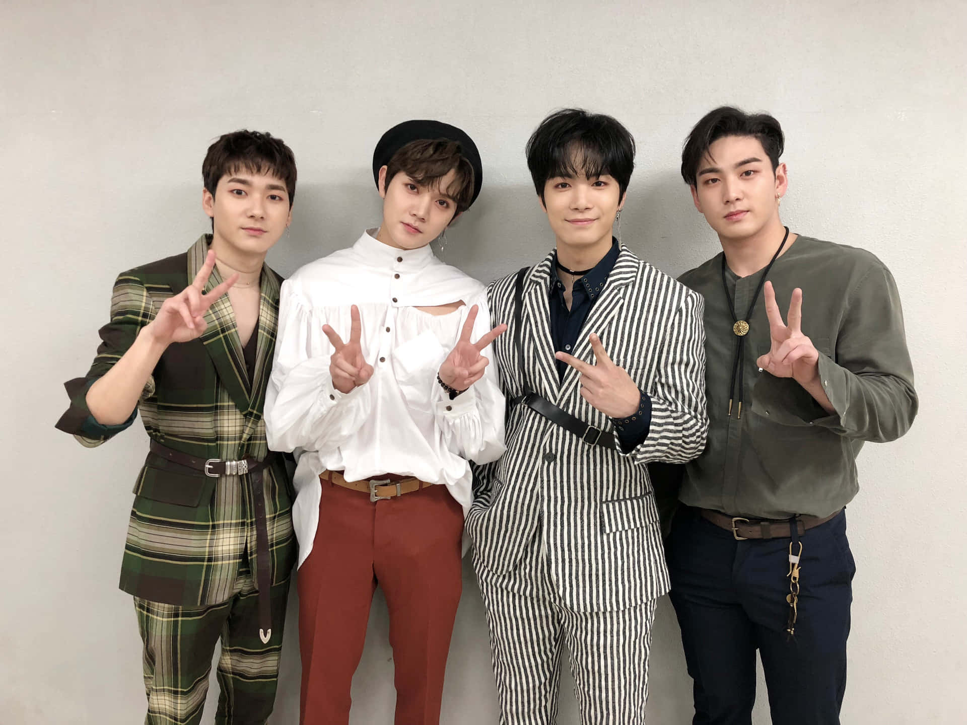 四位時尚男士在攝影棚內擺出和平手勢。 — K Pop 壁紙