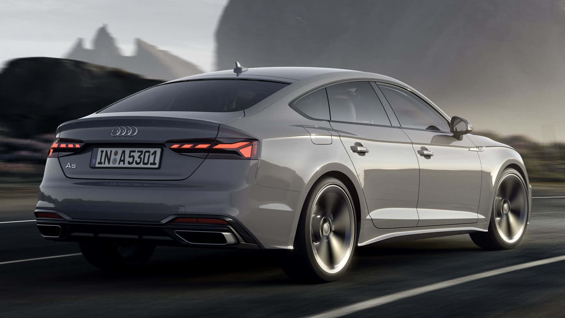 Audi A5 桌布 壁紙 — 一輛時尚的銀色奧迪A5轎跑車沿著山路疾馳，背景是模糊的動感和戲劇性的岩石懸崖。