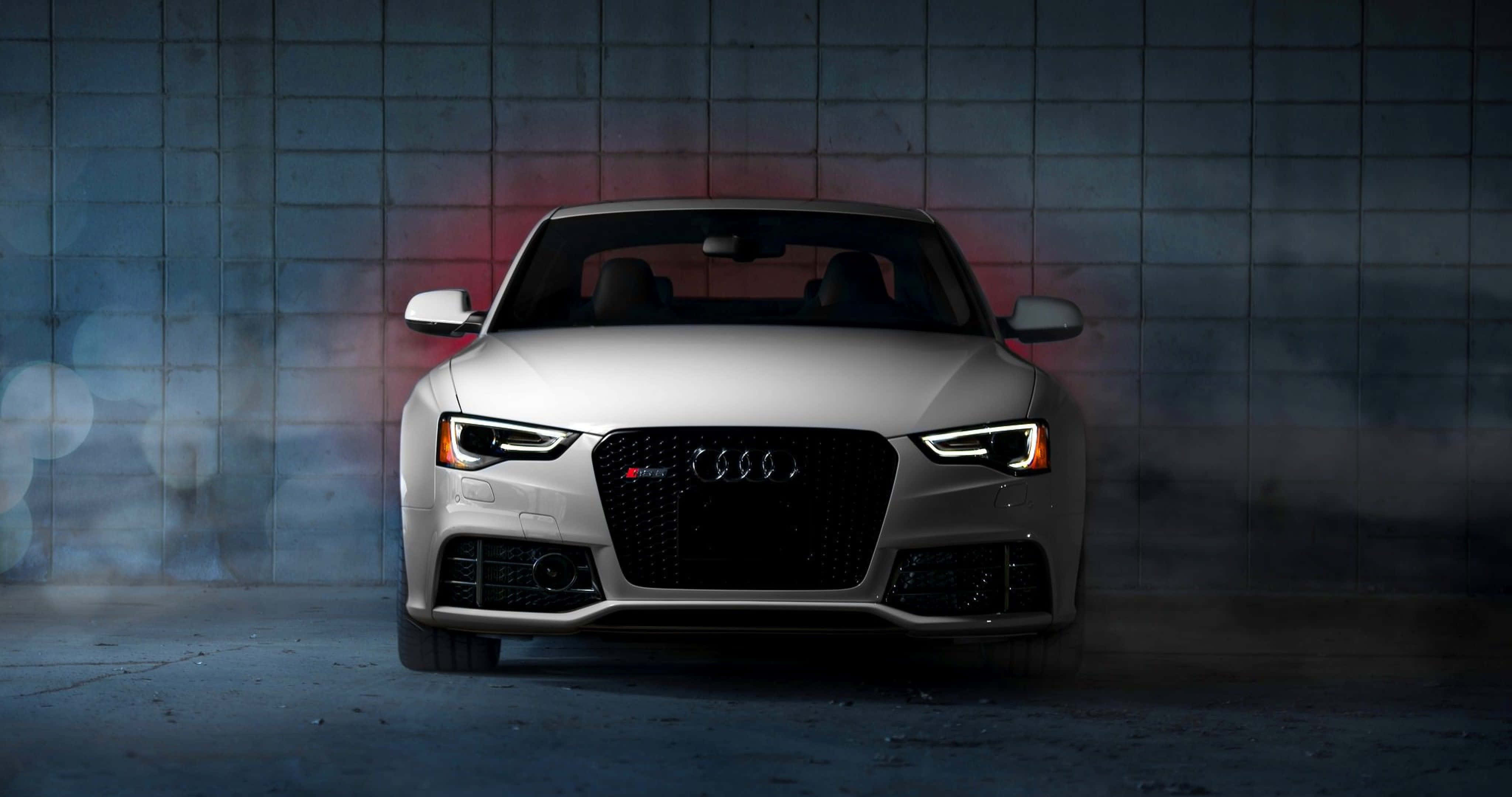 Audi A4 桌布 壁紙 — 一輛時尚的銀色奧迪RS5跑車在戲劇性燈光下，以紋理混凝土牆為背景，伴隨煙霧和散景效果閃耀。