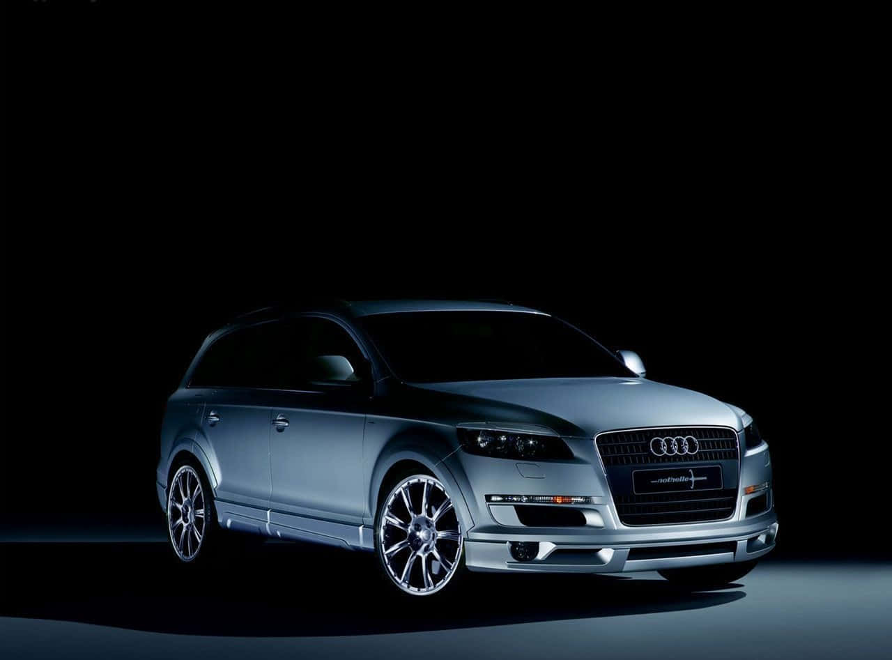 Audi Q7 桌布 壁紙 — 一輛時尚的銀色Audi SUV在漆黑背景下，於戲劇性的工作室燈光中閃耀。