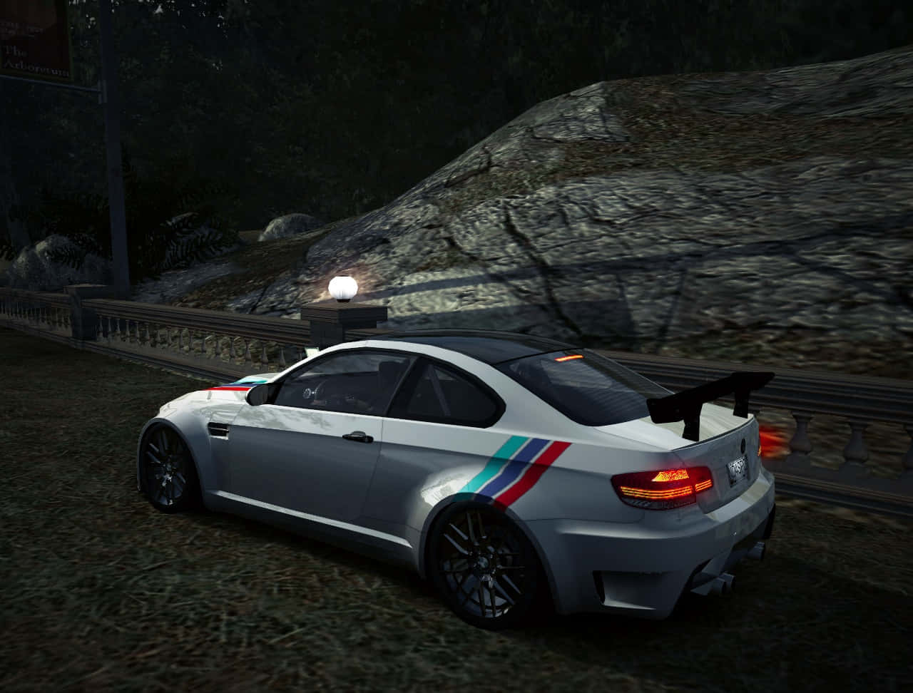  壁紙 — 一輛帶有紅、藍、白條紋的銀色BMW M3 GTR在夜間行駛於被發光路燈照亮的蜿蜒山路上。