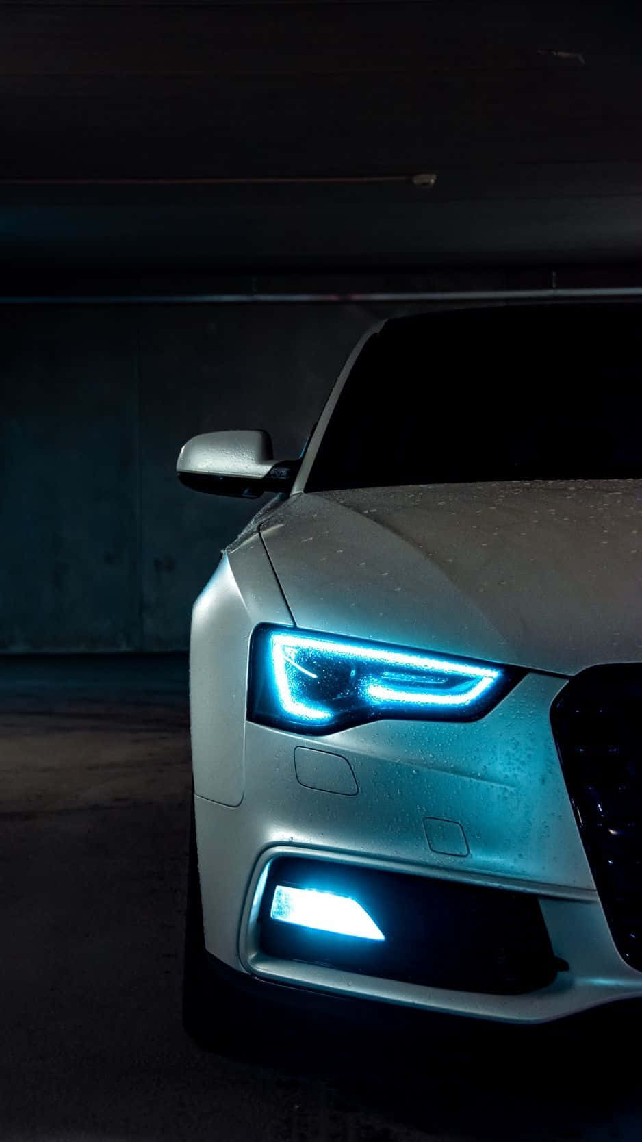 Audi A5 桌布 壁紙 — 一輛銀色汽車的藍色發光車頭燈刺穿潮濕的地下停車場的黑暗。