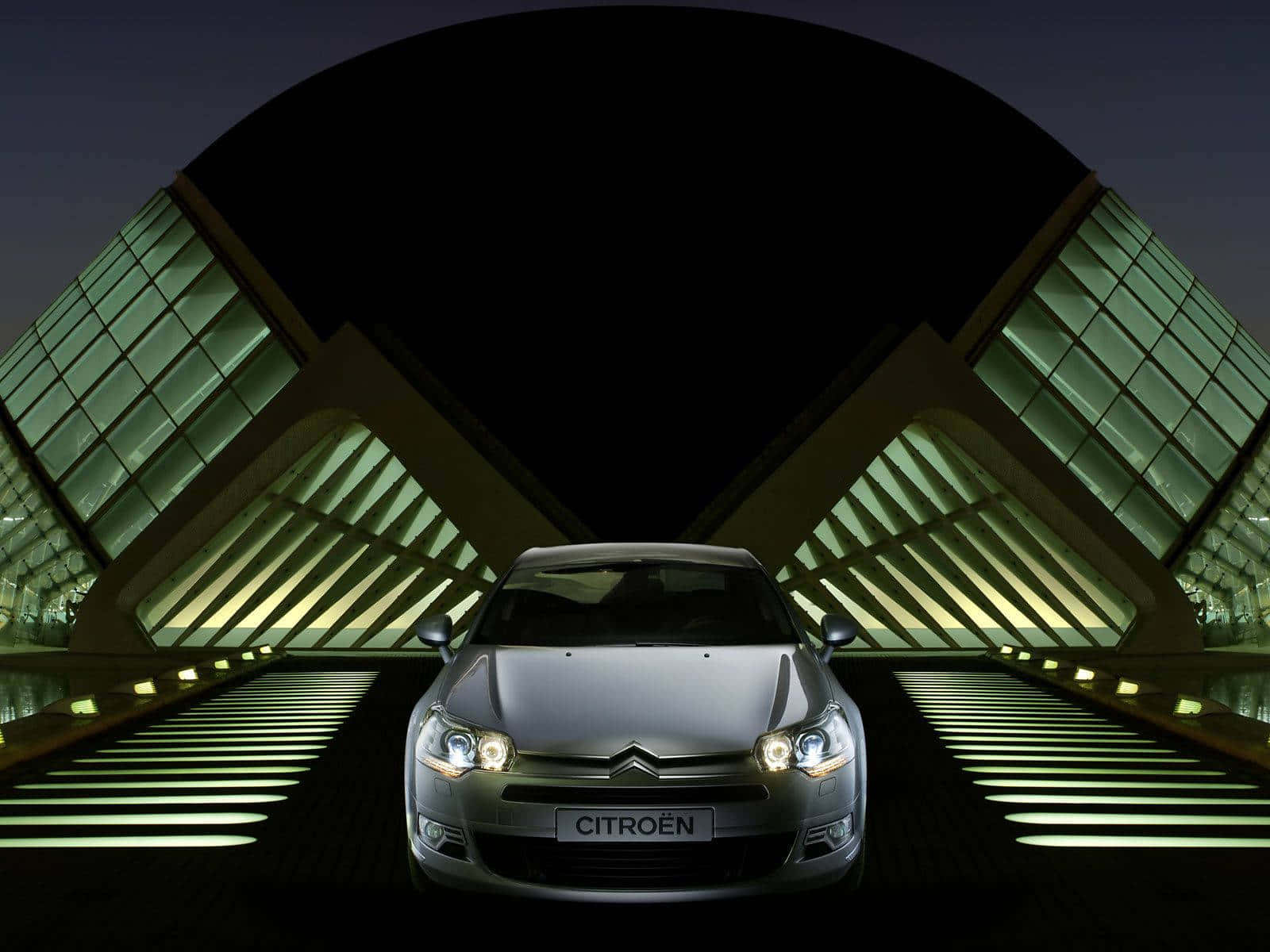 Citroen C2 Super 1600 桌布 壁紙 — 一輛銀色雪鐵龍汽車在夜間未來的玻璃和鋼拱門下，在發光的綠色燈光下閃閃發光。