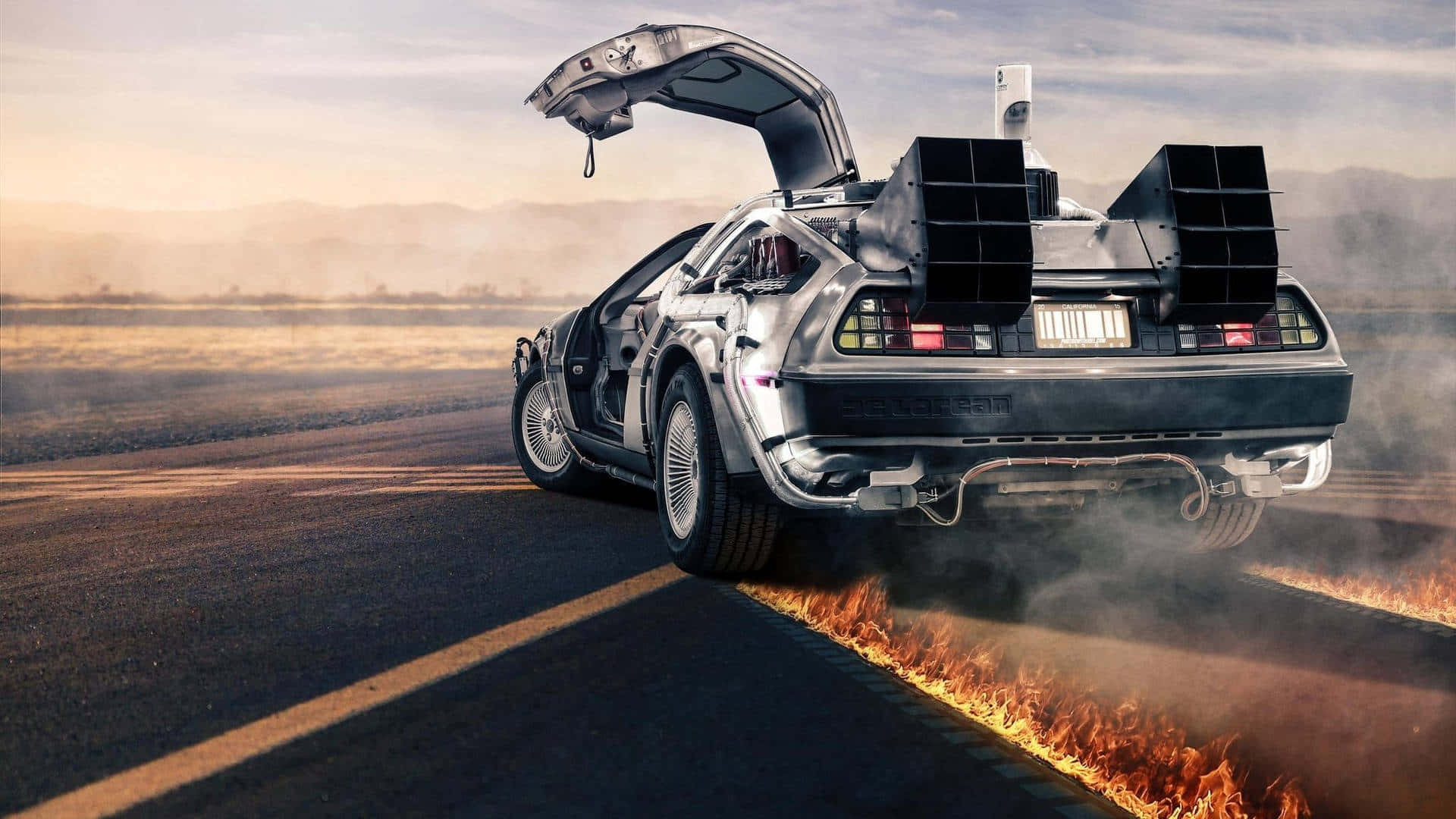  壁紙 — 一架銀色DeLorean，鷗翼車門打開，後輪在沙漠公路上於日落時噴出火焰。