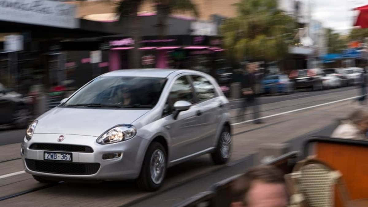 Fiat Punto 桌布 壁紙 — 一輛銀色 Fiat Punto 在繁忙的城市街道上飛馳，動態模糊捕捉了都市的匆忙。